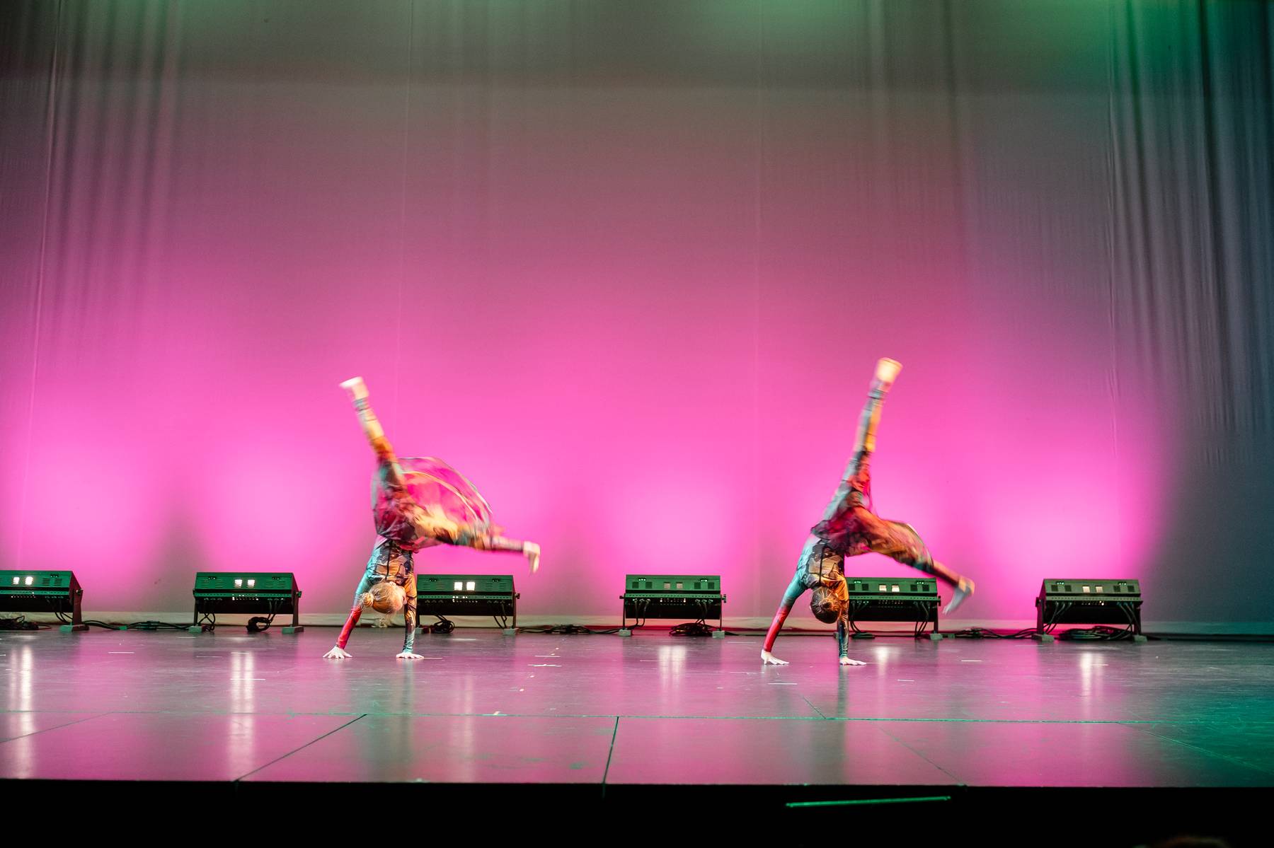 Dancers performing under pink stage lighting