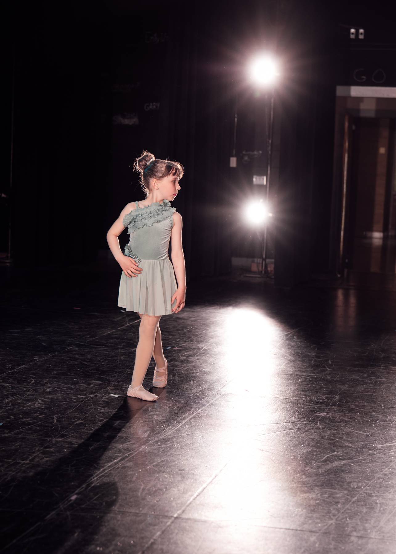 Young ballet dancer standing under stage lights
