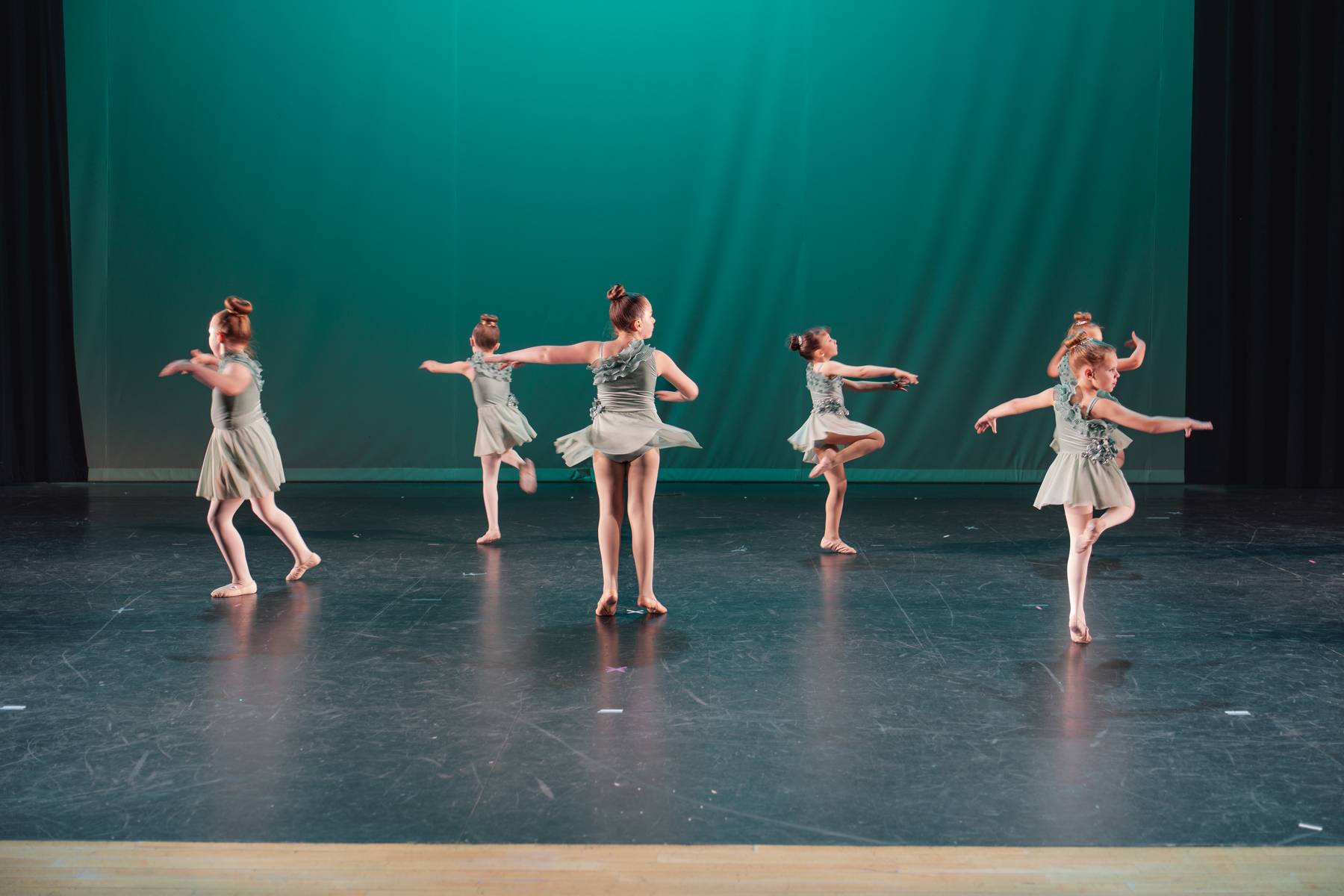 Young dancers performing on a teal-lit stage